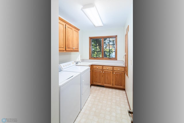 clothes washing area with washer and clothes dryer, cabinets, and sink