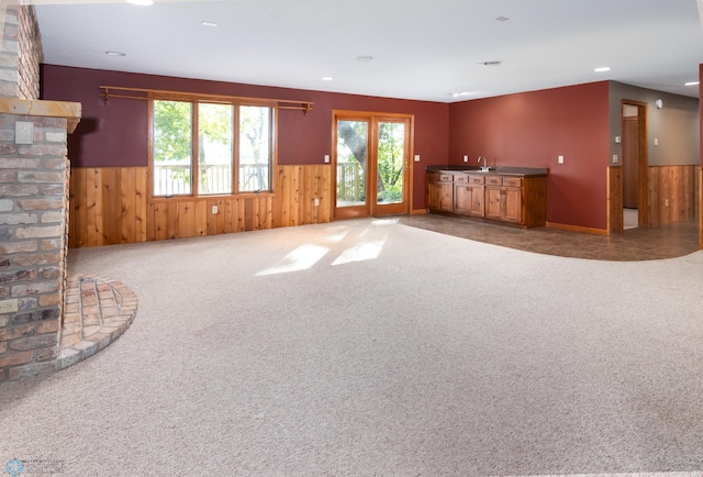 unfurnished living room with carpet and wooden walls