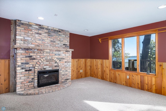 unfurnished living room featuring wooden walls, a fireplace, and carpet flooring