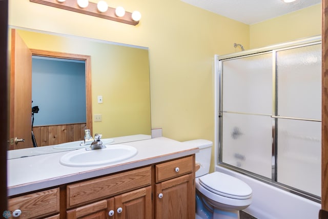 full bathroom with vanity, toilet, a textured ceiling, and combined bath / shower with glass door