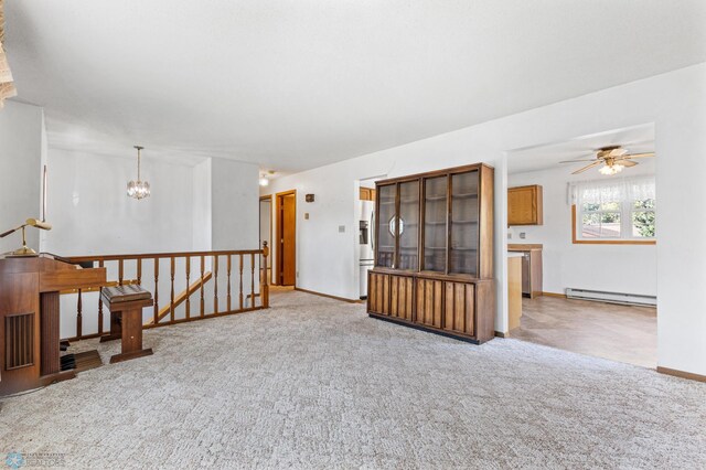 spare room featuring carpet floors, ceiling fan with notable chandelier, and baseboard heating