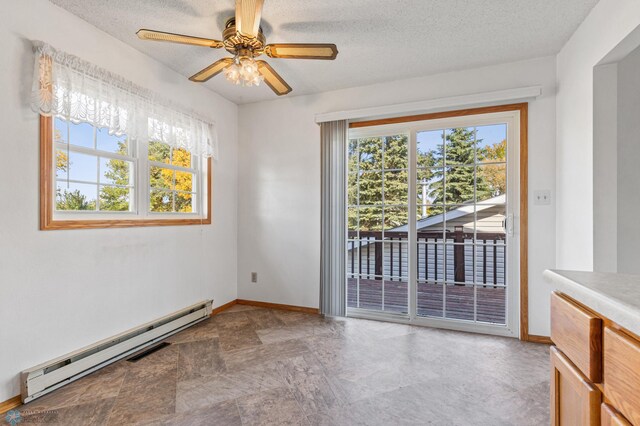 spare room with a textured ceiling, a baseboard heating unit, and plenty of natural light