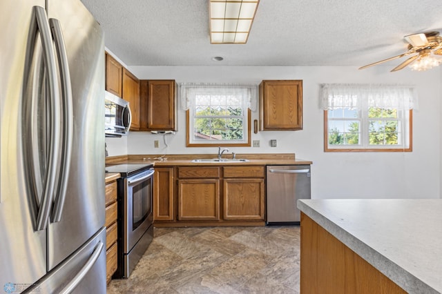 kitchen featuring appliances with stainless steel finishes, a textured ceiling, sink, and ceiling fan