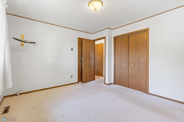 unfurnished bedroom with a closet, light colored carpet, and a textured ceiling