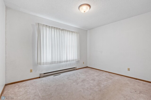 unfurnished room with light colored carpet, a textured ceiling, and baseboard heating