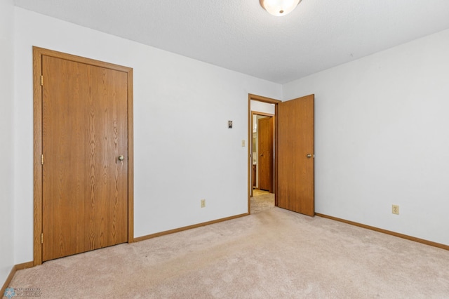 spare room featuring a textured ceiling and light colored carpet