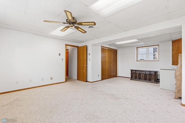 interior space with a drop ceiling, carpet, and ceiling fan