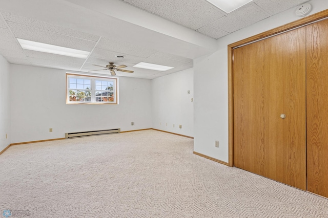 unfurnished bedroom with carpet floors, a drop ceiling, a closet, and a baseboard radiator