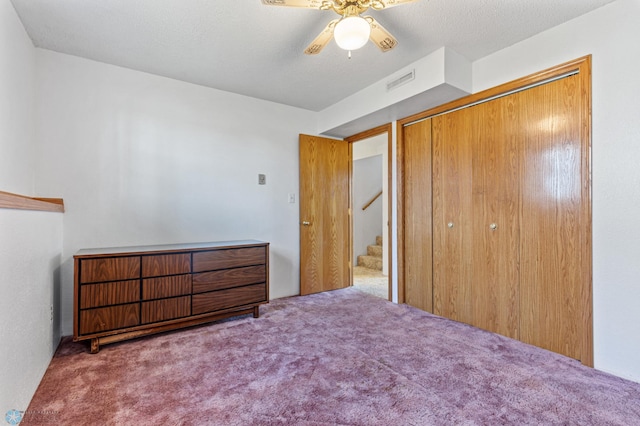 carpeted bedroom with a closet, ceiling fan, and a textured ceiling