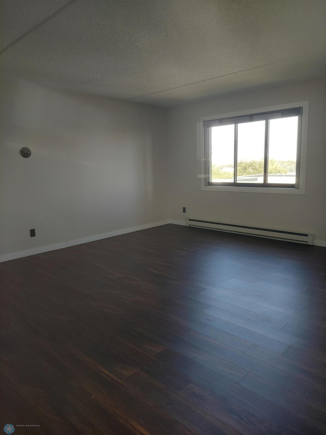 spare room with baseboard heating and dark hardwood / wood-style flooring