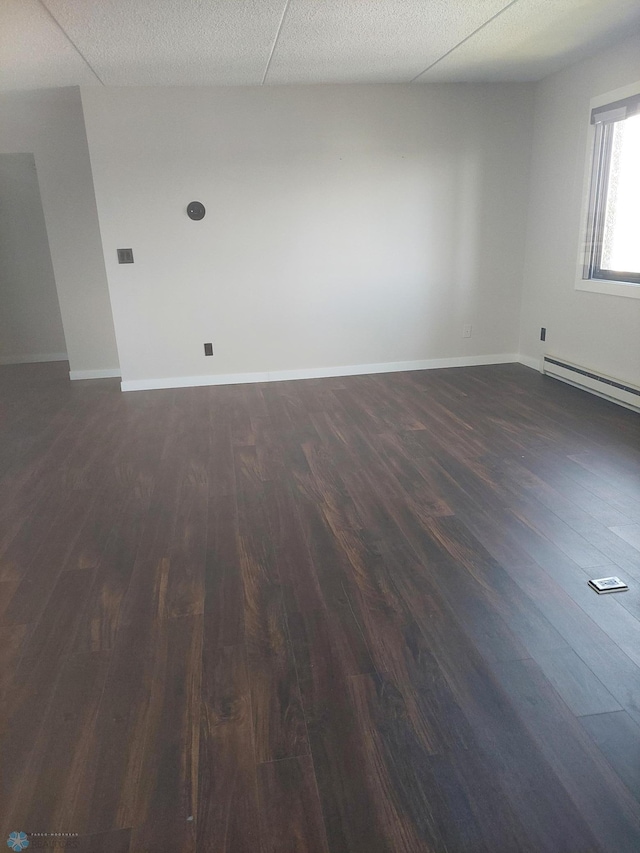 unfurnished room featuring a baseboard heating unit and dark wood-type flooring