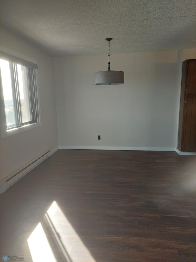 spare room with a textured ceiling, baseboard heating, and dark wood-type flooring