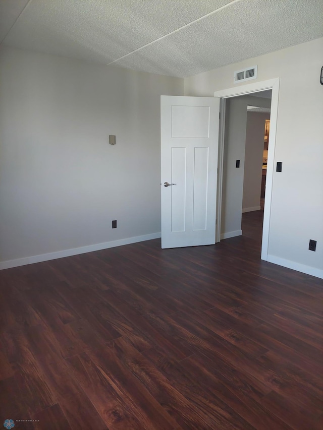 unfurnished room with a textured ceiling and dark hardwood / wood-style floors