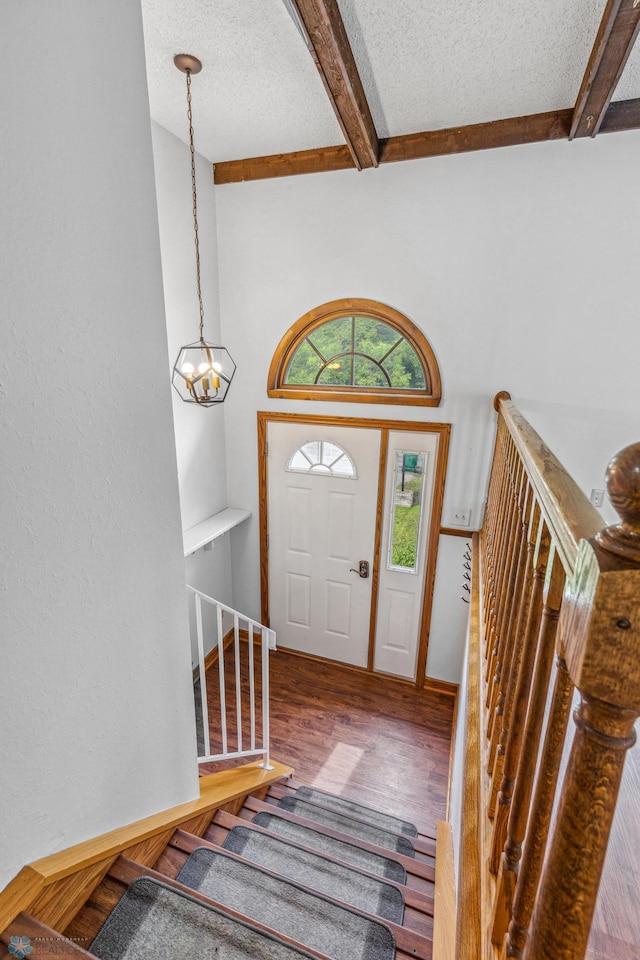 foyer featuring a textured ceiling, wood-type flooring, and beam ceiling