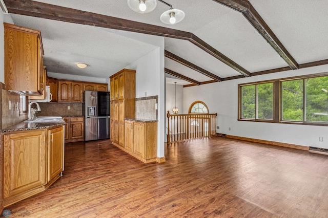 kitchen with dark stone countertops, lofted ceiling with beams, stainless steel fridge with ice dispenser, and decorative light fixtures