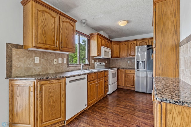 kitchen with a textured ceiling, dark wood-type flooring, sink, backsplash, and white appliances