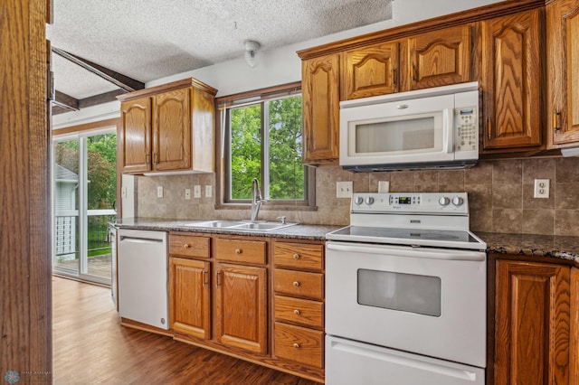 kitchen with white appliances, a textured ceiling, dark hardwood / wood-style floors, and plenty of natural light