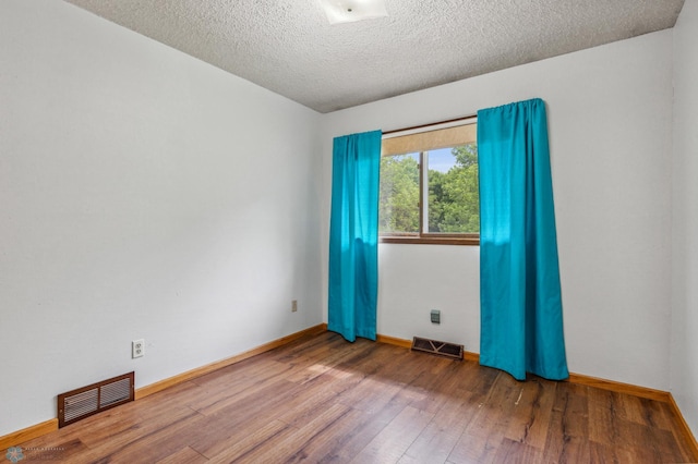 empty room with a textured ceiling and hardwood / wood-style floors