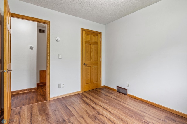 unfurnished bedroom featuring a textured ceiling and hardwood / wood-style floors