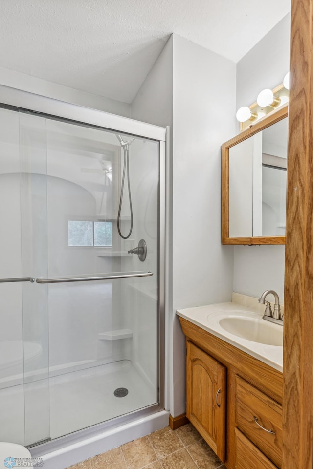 bathroom featuring a textured ceiling, vanity, tile patterned floors, and an enclosed shower