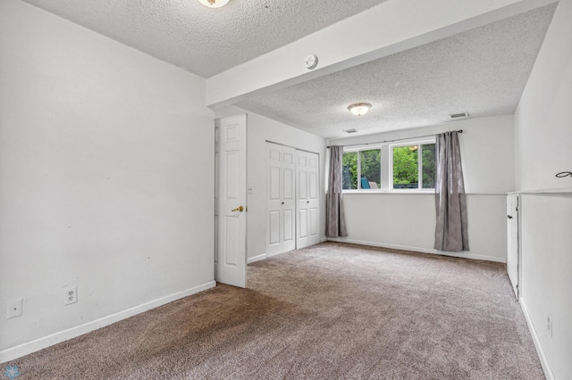 empty room featuring a textured ceiling and carpet