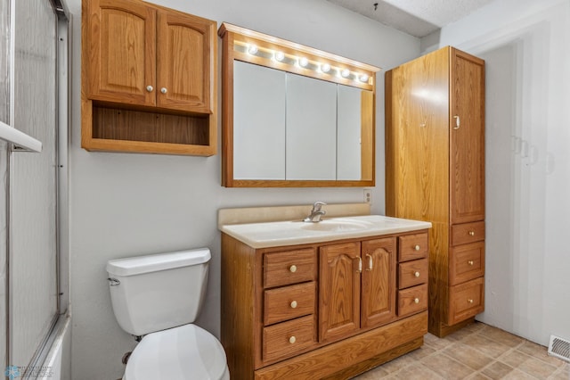 bathroom featuring a textured ceiling, vanity, and toilet