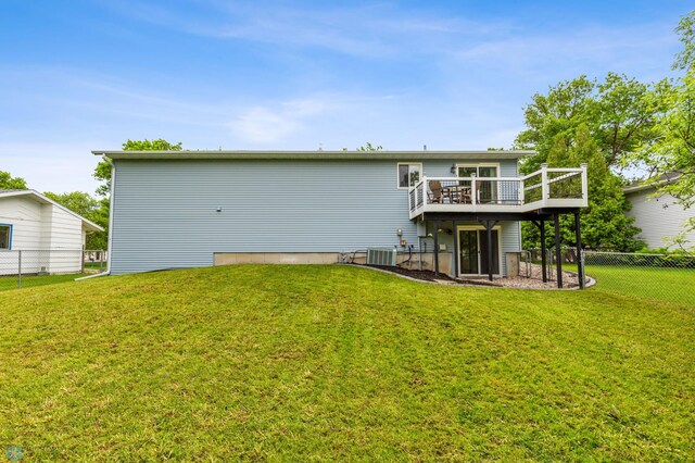 rear view of property featuring cooling unit, a yard, and a deck