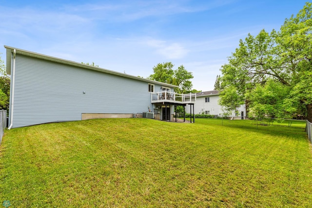 back of property featuring a deck, a lawn, and central AC