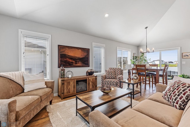 living room featuring hardwood / wood-style floors, vaulted ceiling, and a chandelier