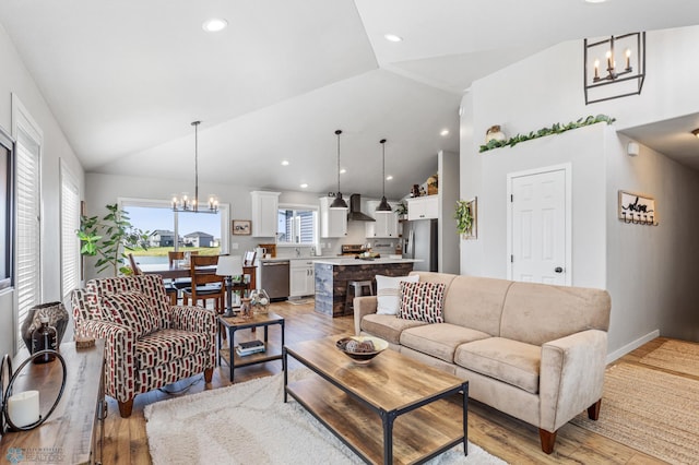 living room with a notable chandelier, light hardwood / wood-style floors, and high vaulted ceiling