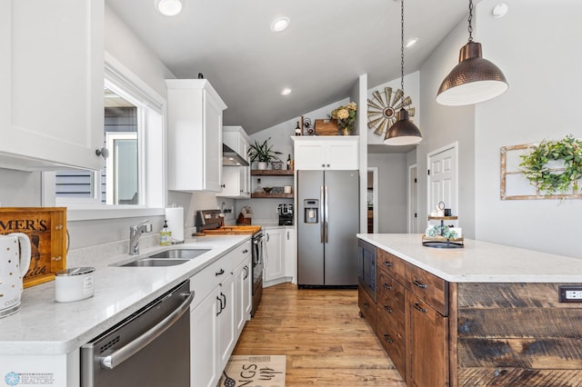 kitchen with white cabinets, hanging light fixtures, light hardwood / wood-style flooring, appliances with stainless steel finishes, and vaulted ceiling