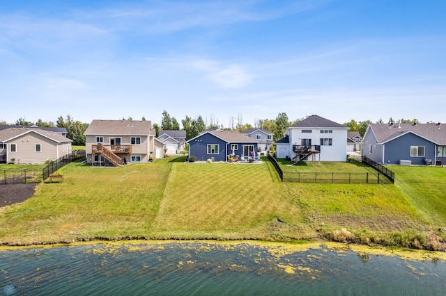 back of house with a yard and a deck with water view