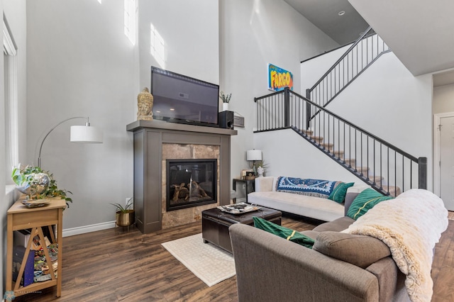 living room with a high ceiling, a fireplace, and dark wood-type flooring