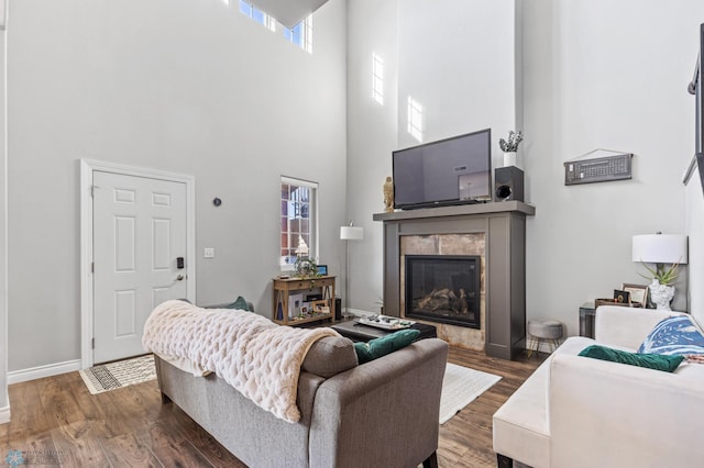 living room with a towering ceiling, a fireplace, and dark hardwood / wood-style flooring