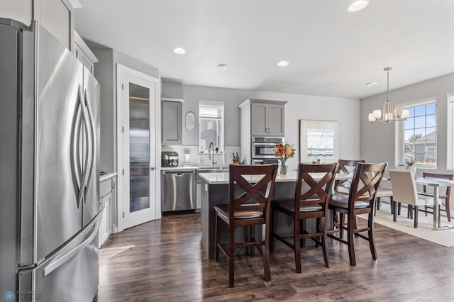 kitchen featuring appliances with stainless steel finishes, a kitchen island, dark hardwood / wood-style flooring, gray cabinets, and sink