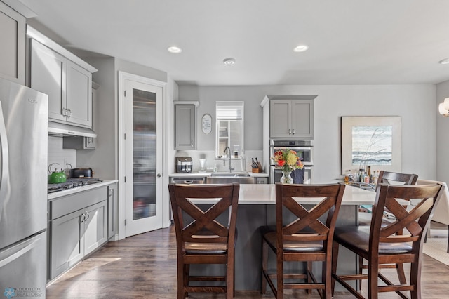 kitchen featuring appliances with stainless steel finishes, dark wood-type flooring, and gray cabinetry