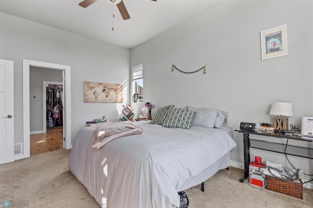 carpeted bedroom featuring a closet, a walk in closet, and ceiling fan