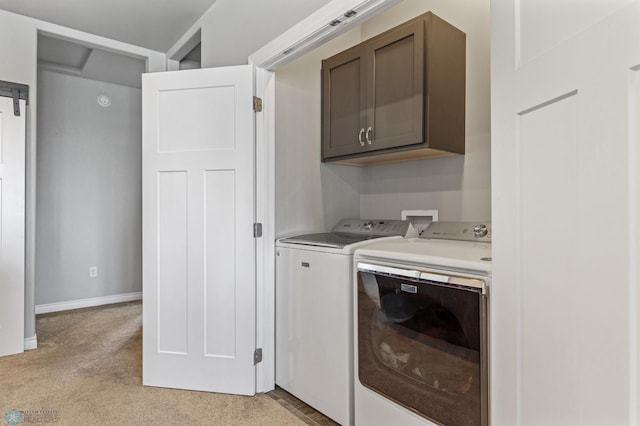 clothes washing area with cabinets, light carpet, and washer and dryer