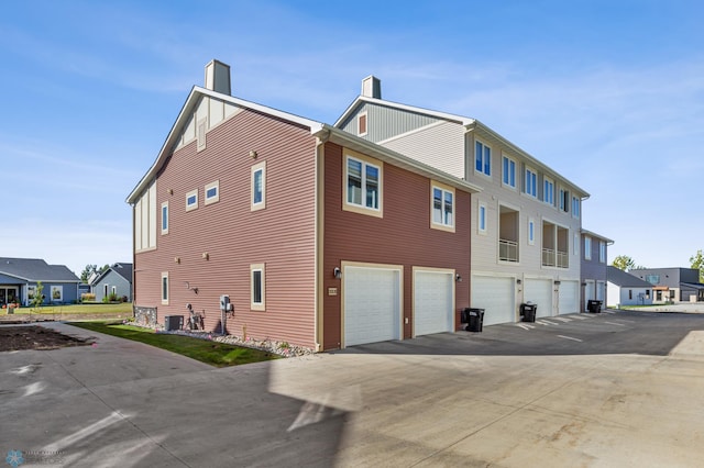 view of property exterior featuring central AC unit and a garage