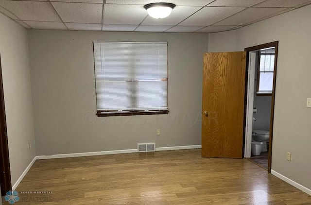 spare room with a drop ceiling and light wood-type flooring