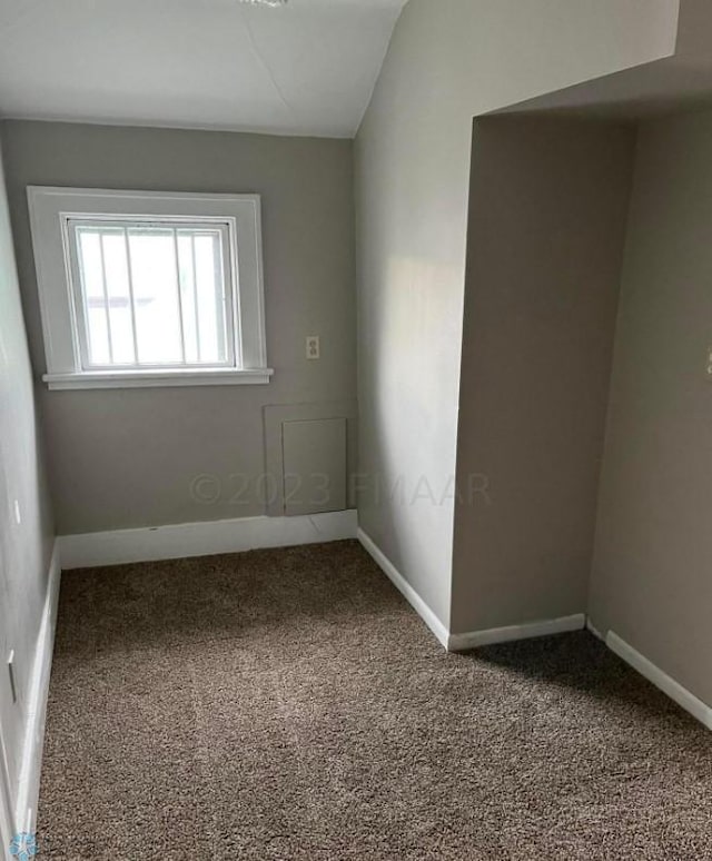 carpeted empty room with vaulted ceiling