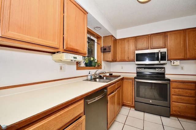 kitchen featuring stainless steel appliances, a textured ceiling, light tile patterned floors, and sink