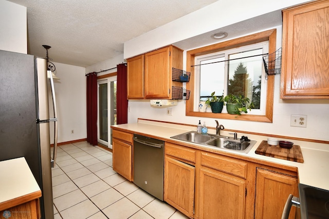 kitchen with light tile patterned floors, a textured ceiling, stainless steel appliances, and sink