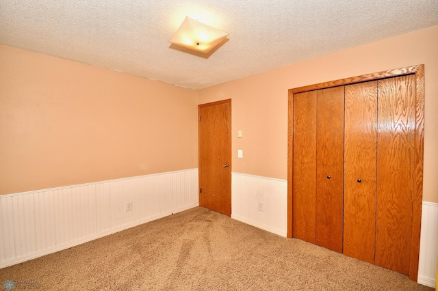 unfurnished bedroom featuring light carpet, a textured ceiling, and a closet