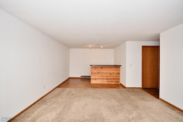 carpeted spare room featuring a baseboard heating unit and rail lighting