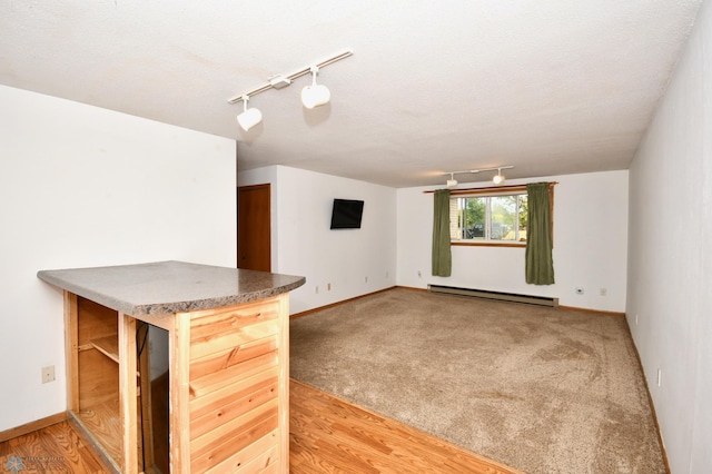 interior space featuring a textured ceiling, rail lighting, hardwood / wood-style floors, and a baseboard heating unit