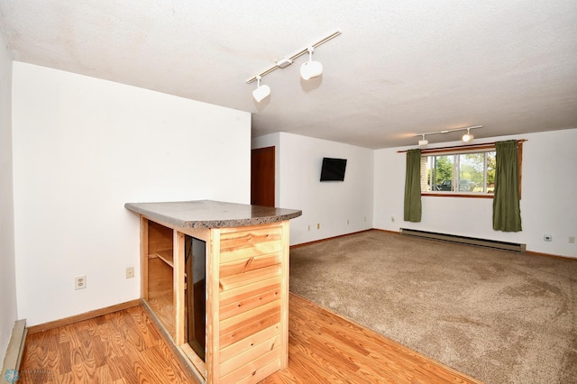 unfurnished living room with track lighting, a baseboard radiator, and hardwood / wood-style floors