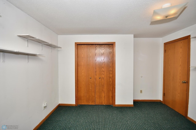 unfurnished bedroom with a textured ceiling and dark colored carpet