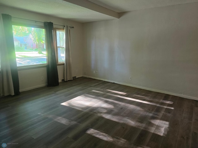 unfurnished room featuring beamed ceiling and dark hardwood / wood-style flooring