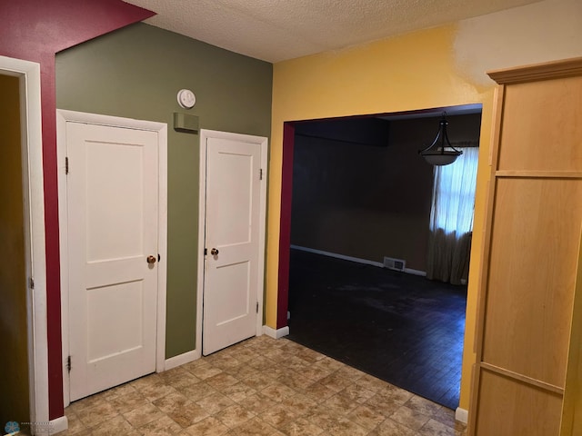 corridor featuring a textured ceiling and light wood-type flooring